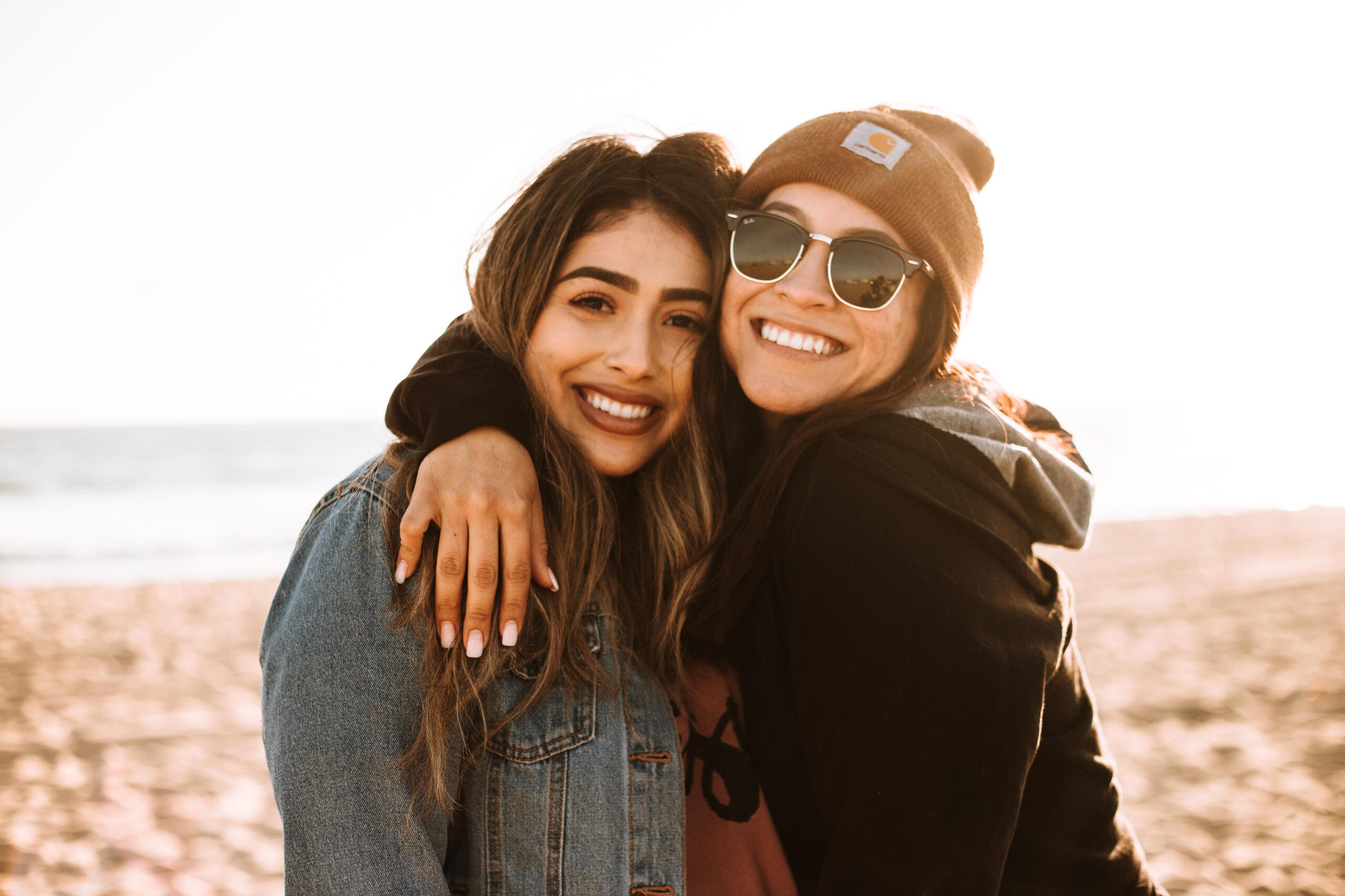 Photograph of two women hugging on a beach